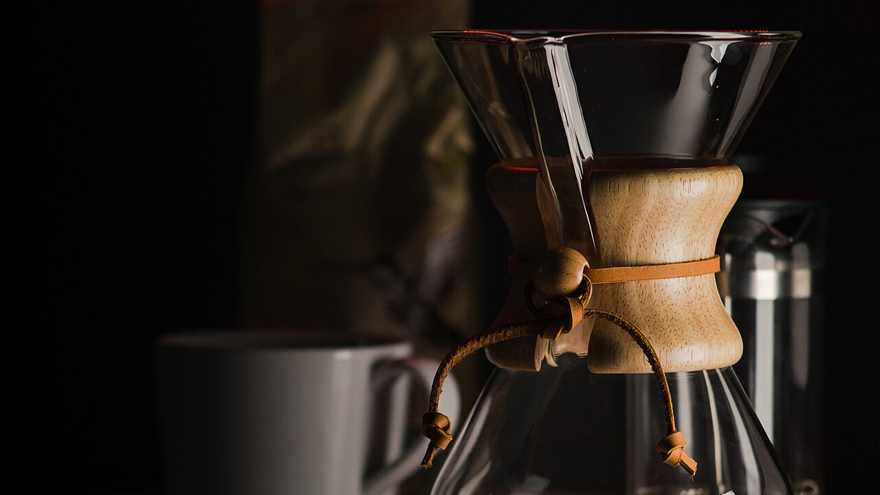 Chemex pour-over coffeemaker on a counter with a mug behind